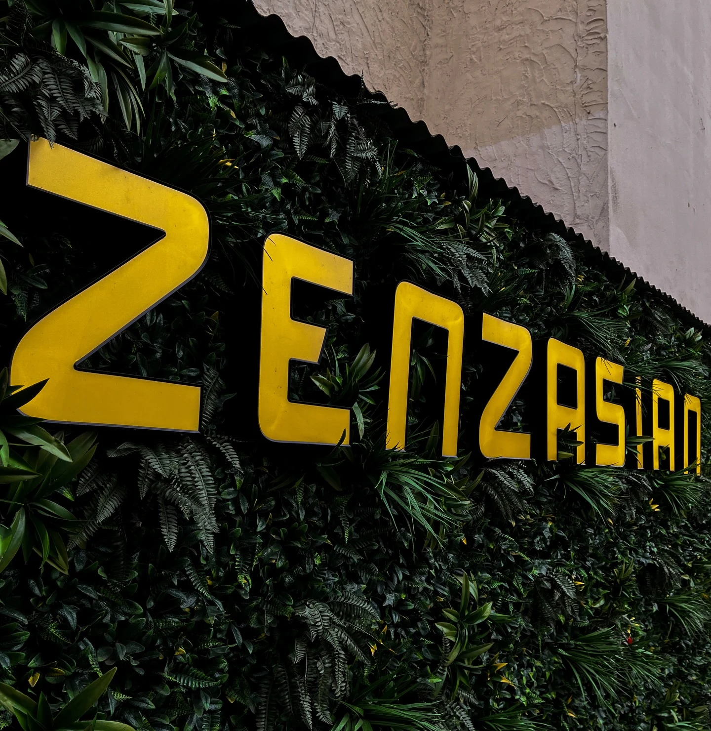 Der Zenzasian-Schriftzug an der Pflanzenwand